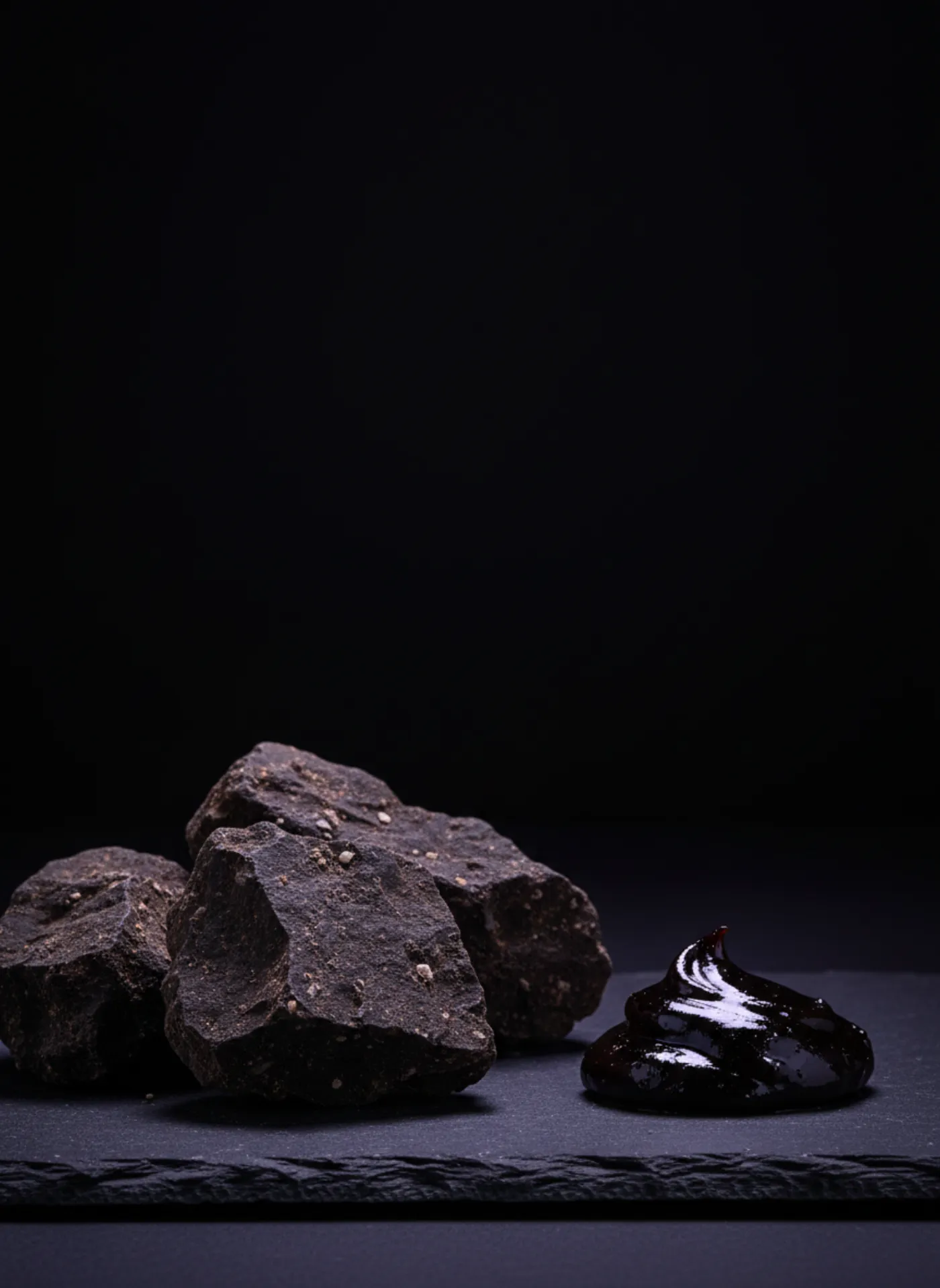 Raw shilajit-bearing rock beside glossy purified Altai resin